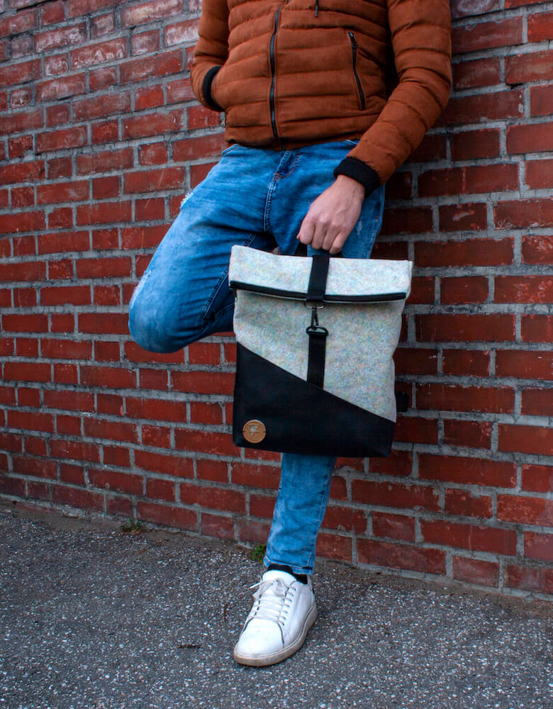 Personne appuyée sur un mur tenant un sac à dos éco-responsable Feeling Felt