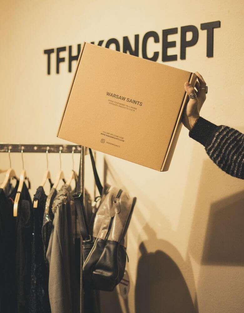 Una caja de cartón junto a varias prendas de ropa